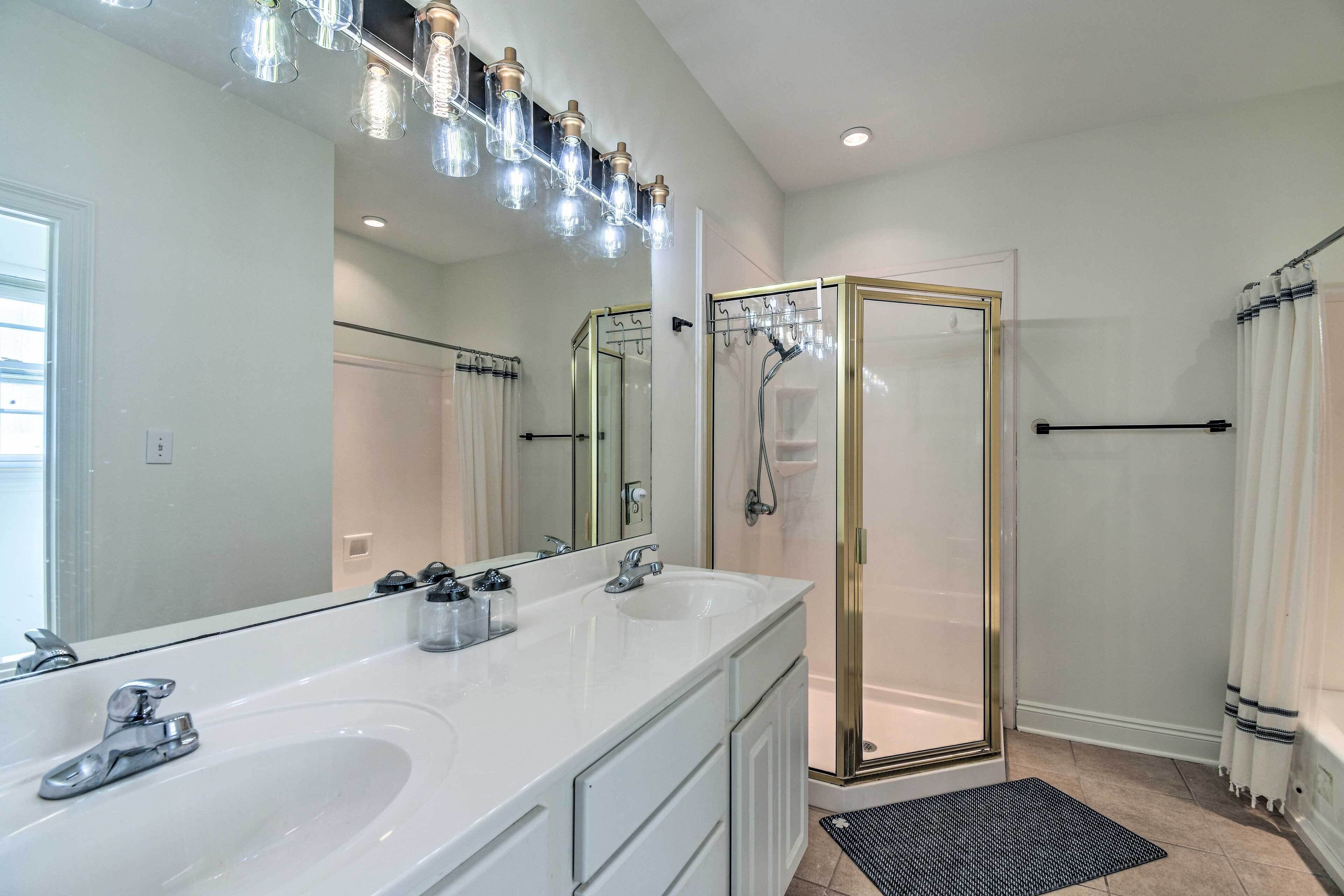 Une salle de bain moderne avec une douche à parois de verre, un grand miroir et un meuble-lavabo à deux vasques.