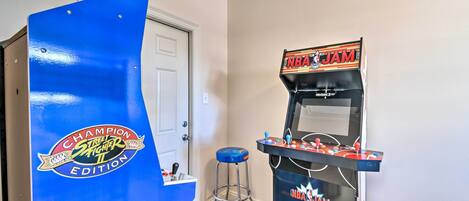 A room with a blue arcade machine labeled "NBA JAM" and a door with a "Champion Street Fighter II" sticker.