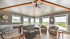Um quarto espaçoso com sofá cinzento, poltrona estampada e mesa de madeira.