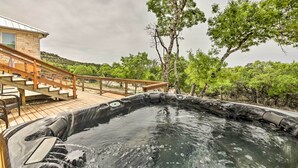 Uma banheira de hidromassagem com um deck de madeira e escadas que levam a um edifício.