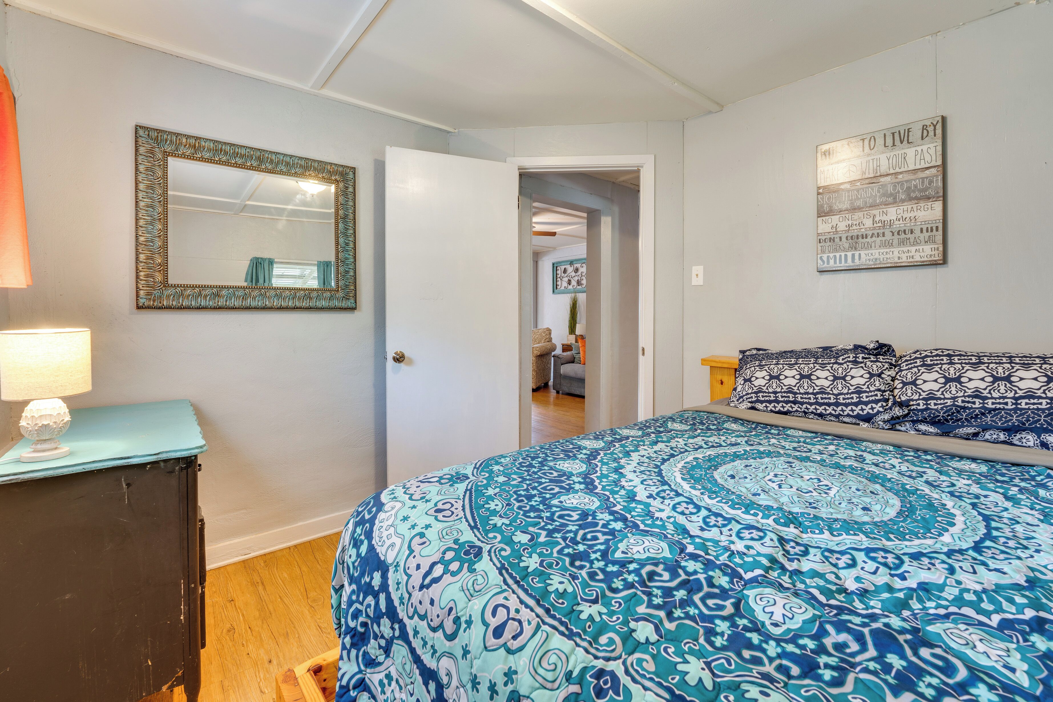 A bedroom with a bed, a dresser, a mirror, and a motivational quote on the wall.