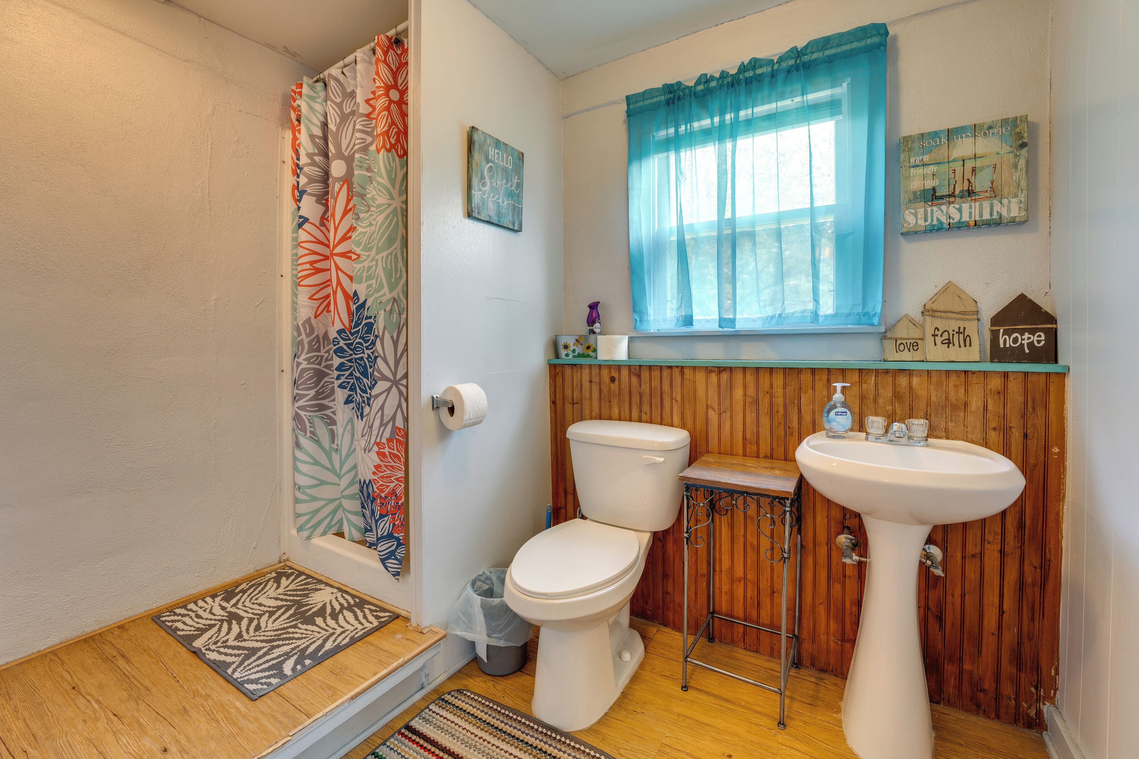 A bathroom with a wooden vanity, a toilet, a sink, and a shower curtain.