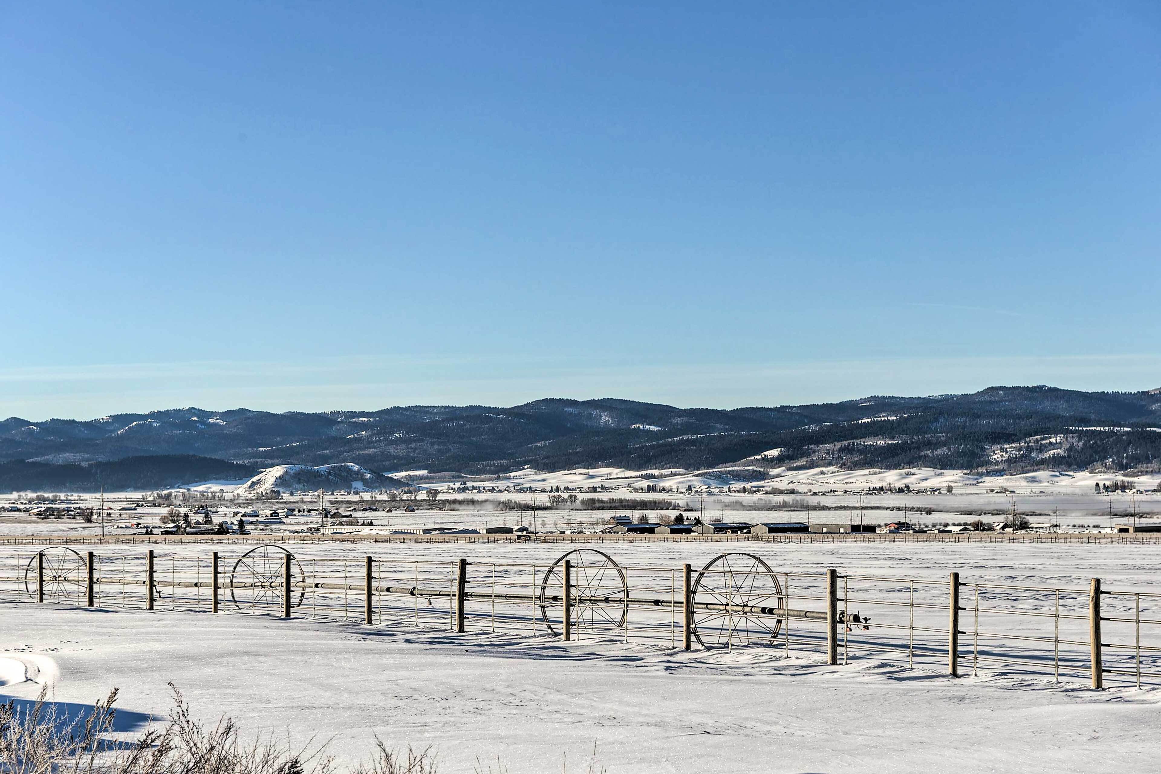Schneebedeckte Landschaft mit einem Zaun und Bergen im Hintergrund.