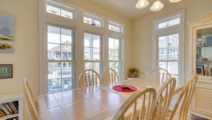 Un espace repas comprenant une grande table, plusieurs chaises et de grandes fenêtres décorées de motifs en forme d’étoiles.