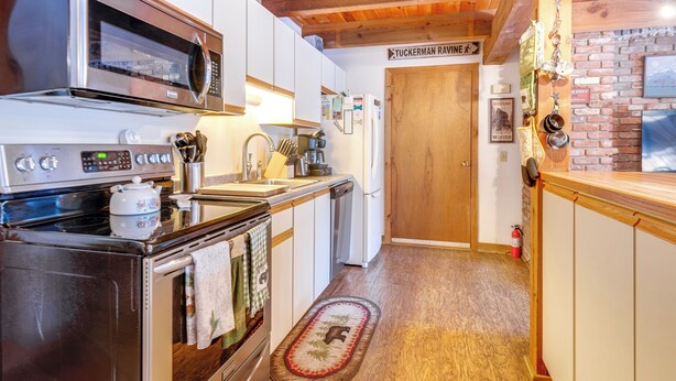 Una cucina con forno a microonde, piano cottura, lavello e mobili in legno. Un cartello appeso al muro recita "Tuckerman Rawine".