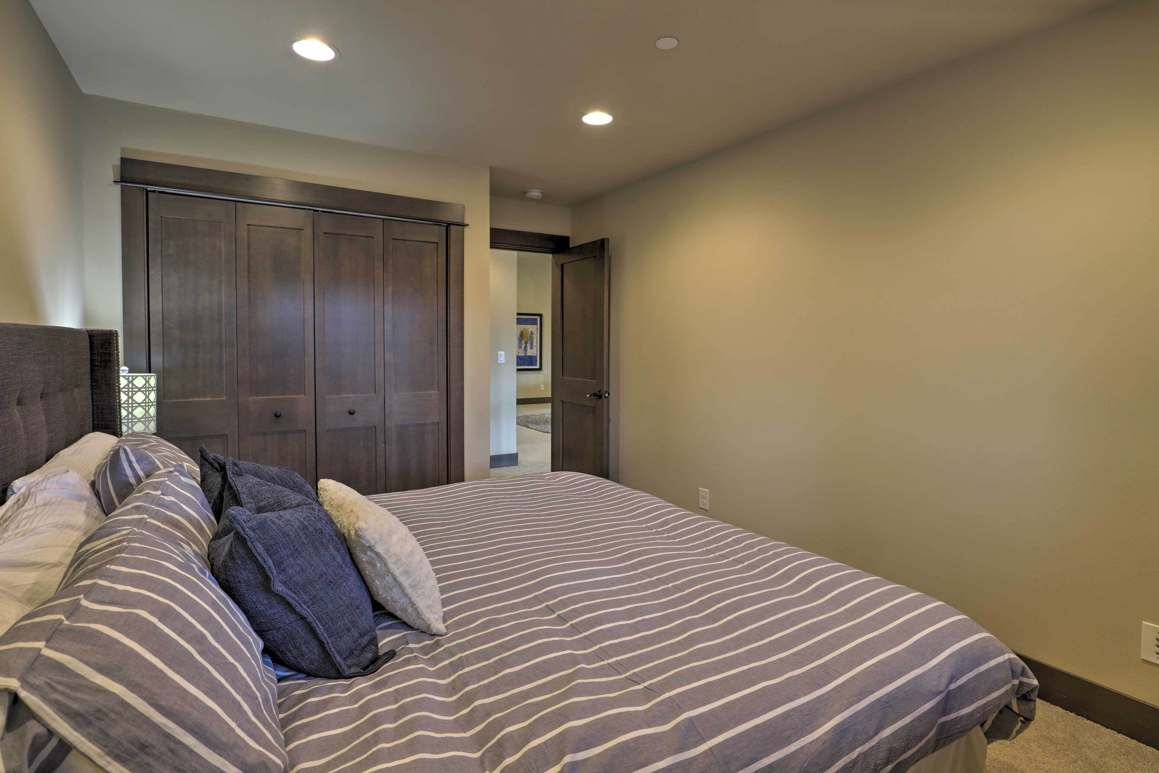 A bedroom with a large bed, dark wooden wardrobe, and a door leading to another room.