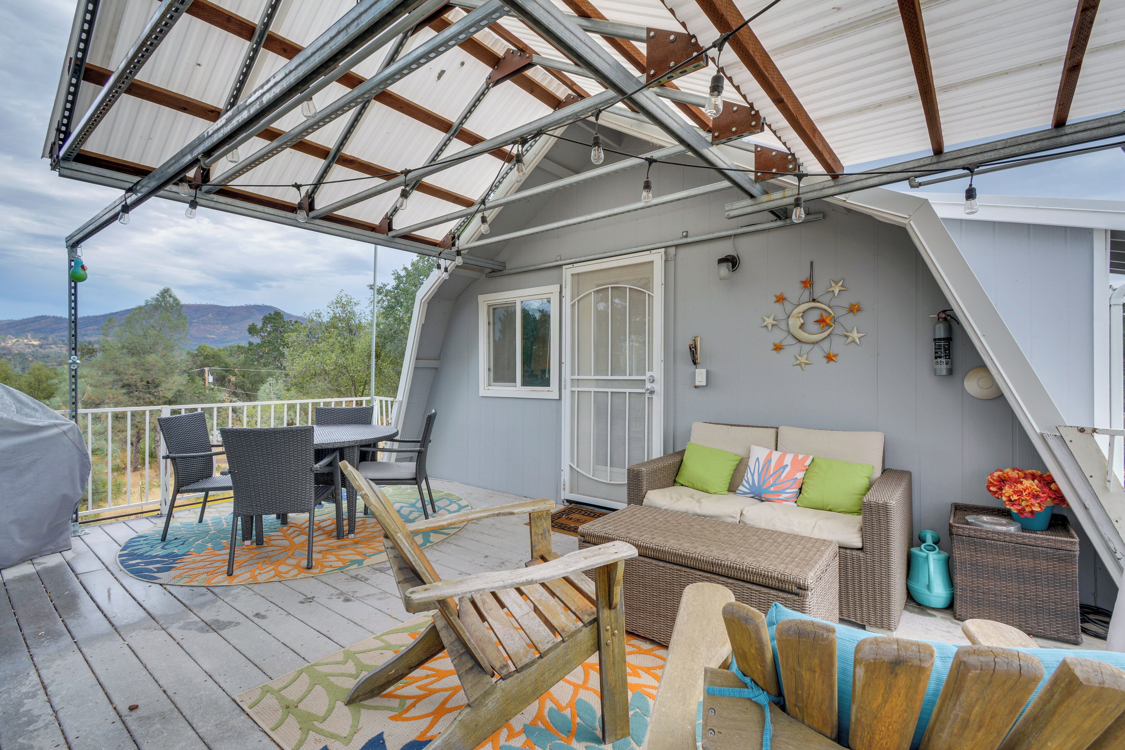 A covered deck with outdoor furniture, a clock, and a view of the landscape.