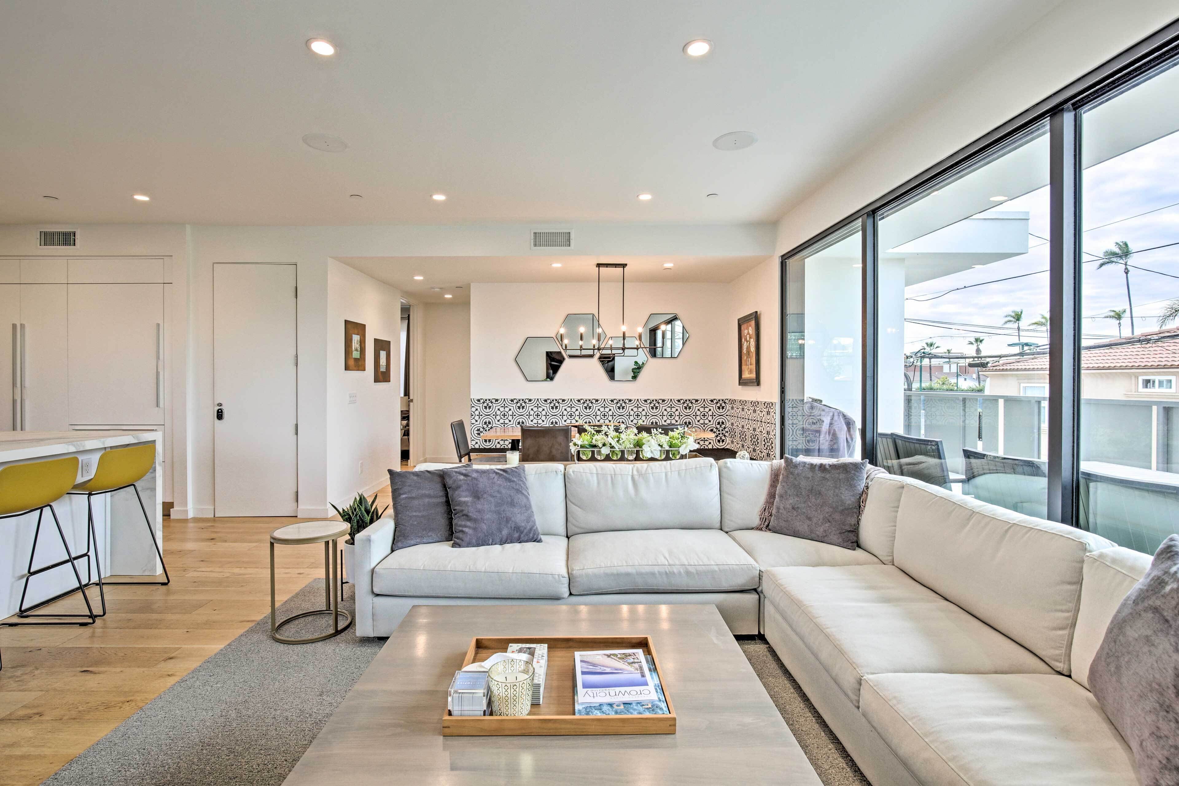 Una sala de estar moderna con un sofá modular, una mesa de centro y un comedor con sillas amarillas.
