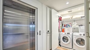 Een kleine wasruimte met een wasmachine, droger en gestapelde wasmanden.