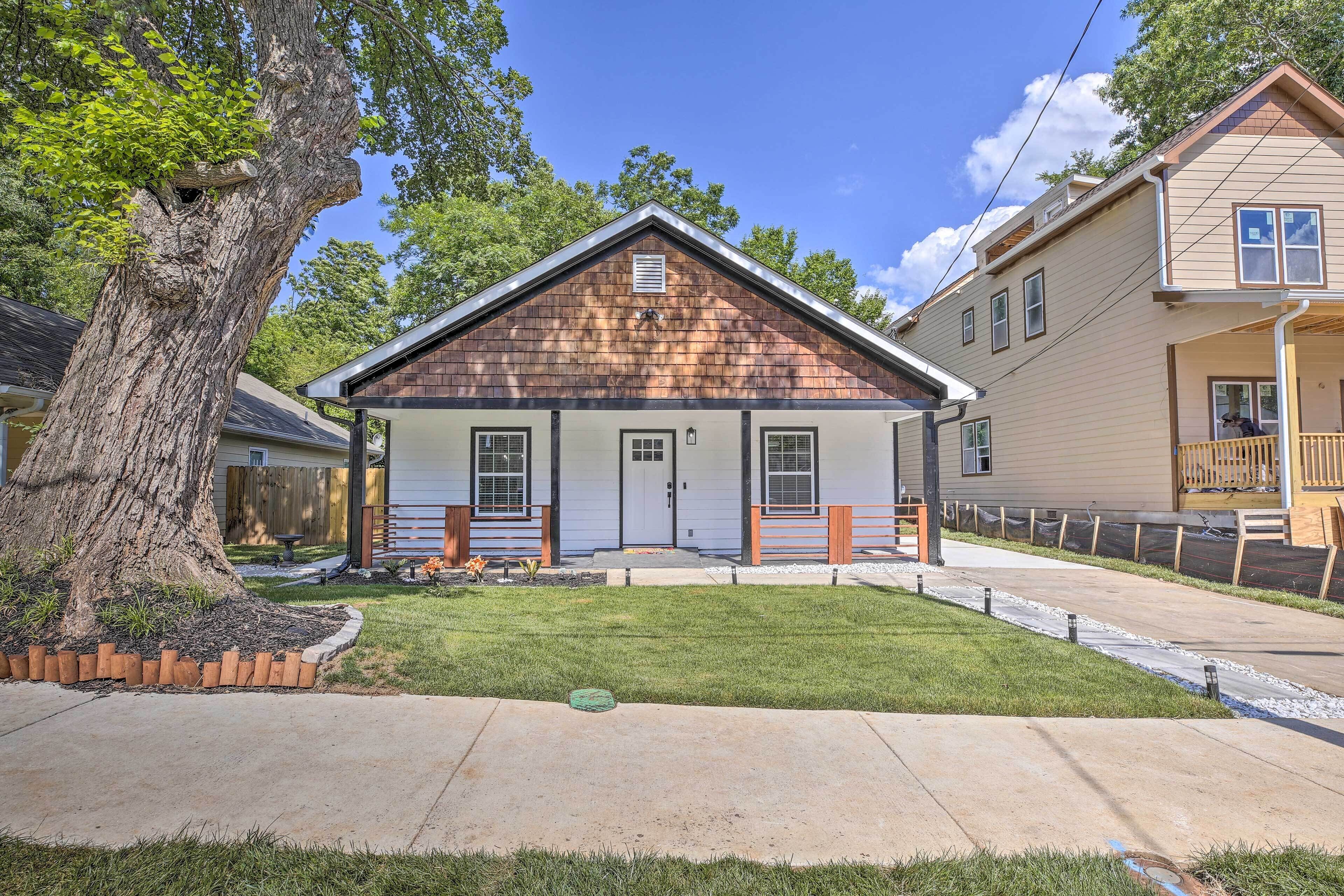 A single-story house with a front porch, a large tree, and a well-maintained lawn.
