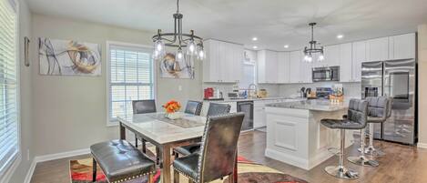 A modern kitchen with white cabinets, stainless steel appliances, and a dining area with a table and chairs.