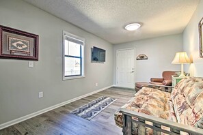 A living room with a patterned sofa, a wooden coffee table, a rug, and a door leading to another room. - Boat Dock, Lake-view Decks! Ozarks Reunion Retreat (Sunrise Beach)