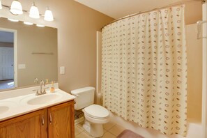 Un baño con lavamanos doble, inodoro y cortina de ducha con diseño de hojas.