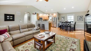 A spacious living room with a leather sofa, a wooden coffee table, and a ceiling fan.