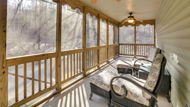 A covered porch with wicker furniture and a ceiling fan.