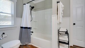 Ein Badezimmer mit Toilette, einer Duschkabine, einem Handtuchhalter und einer weißen Tür.