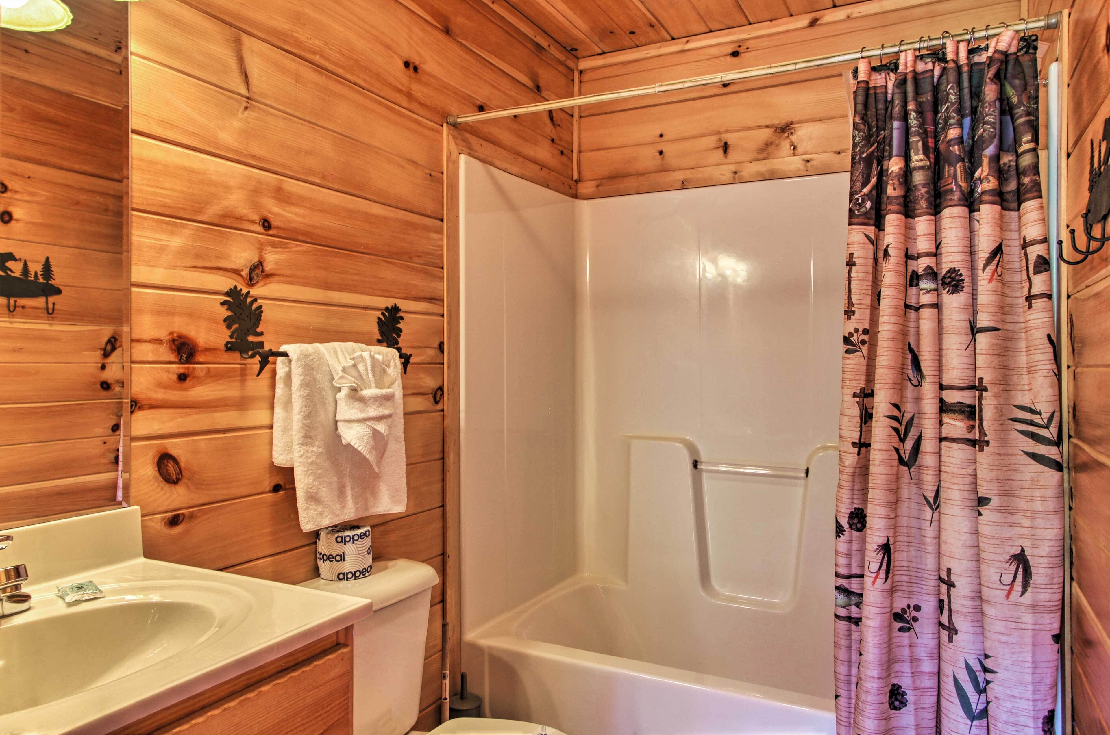 A wooden cabin bathroom with a bathtub, a sink, and a toilet.