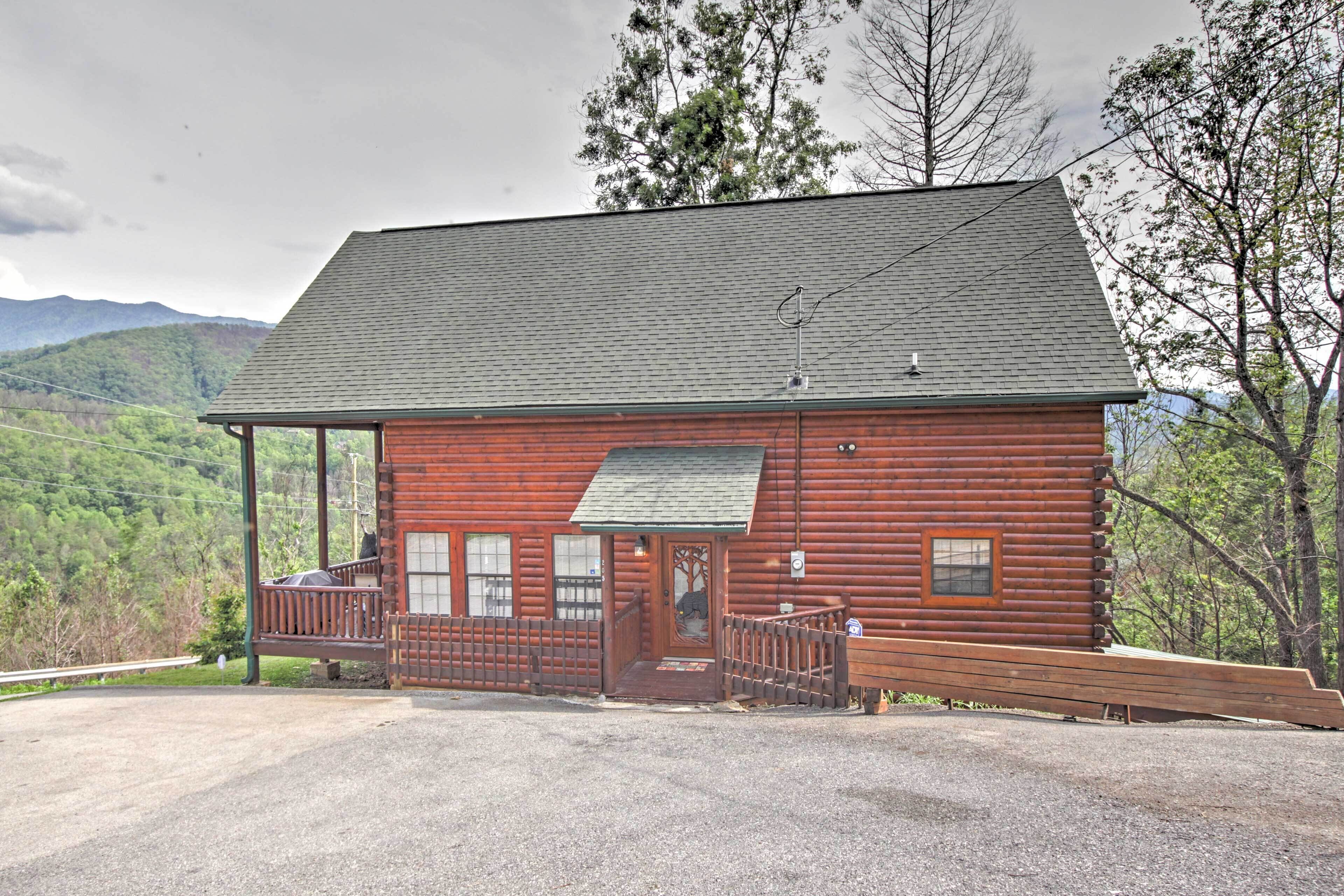A log cabin with a porch, a front door, and a small staircase leading to a deck.