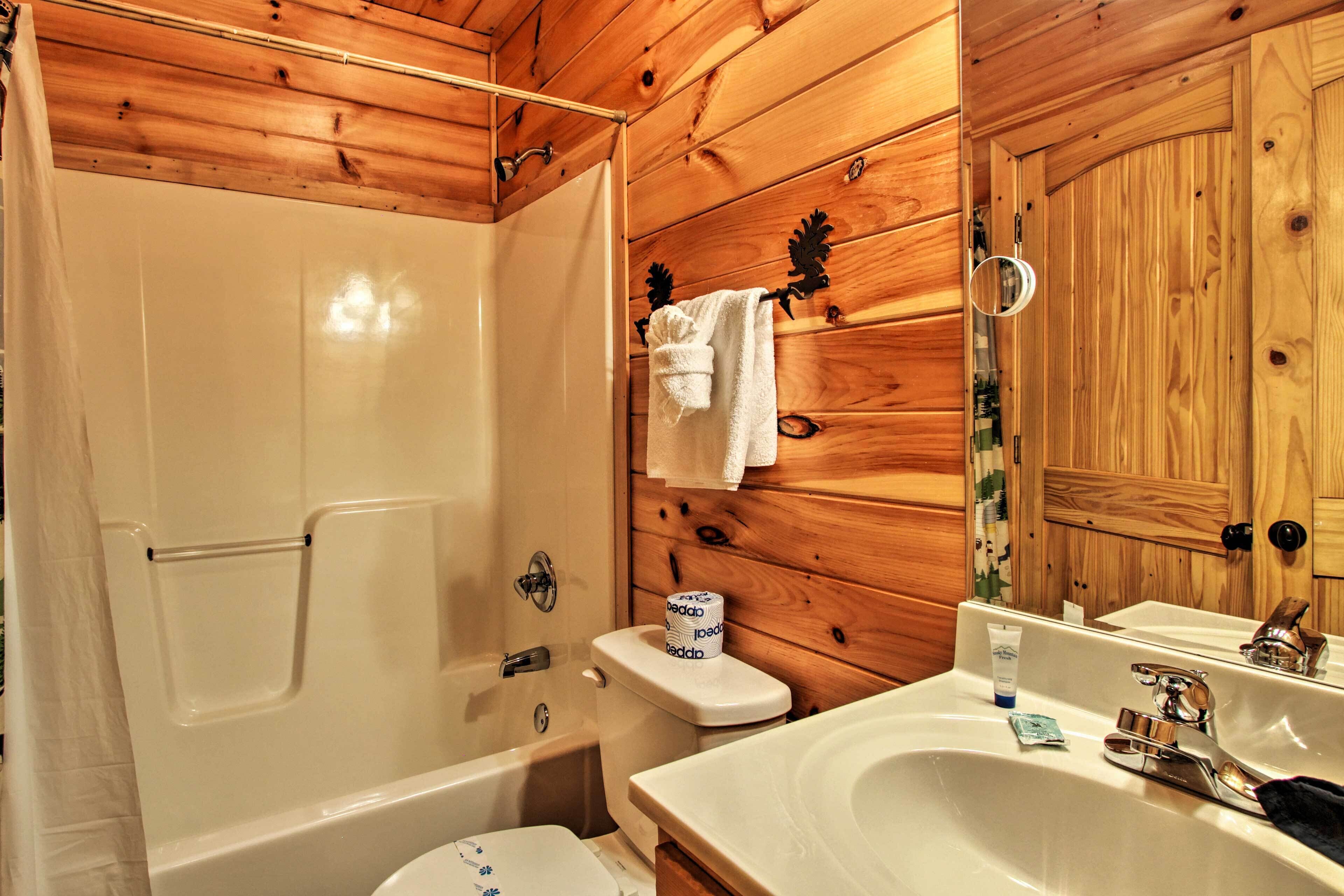 Un baño con detalles de madera, una bañera, inodoro y un lavabo con espejo.