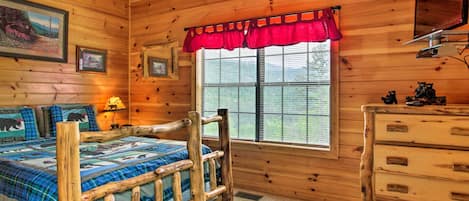 Una habitación de cabaña de madera con cama, cómoda y ventana con persianas.