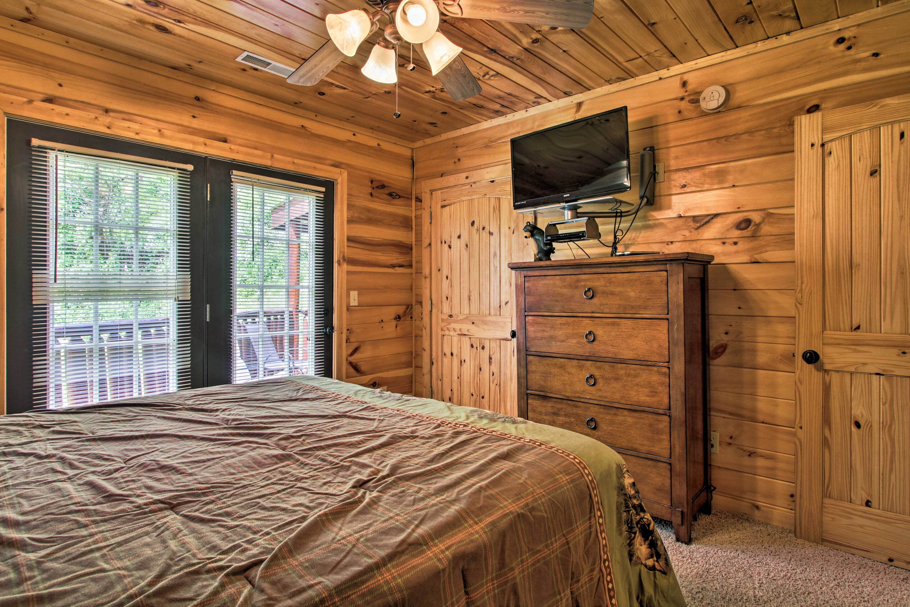 Un dormitorio de cabaña de madera con cama, cómoda y ventilador de techo.
