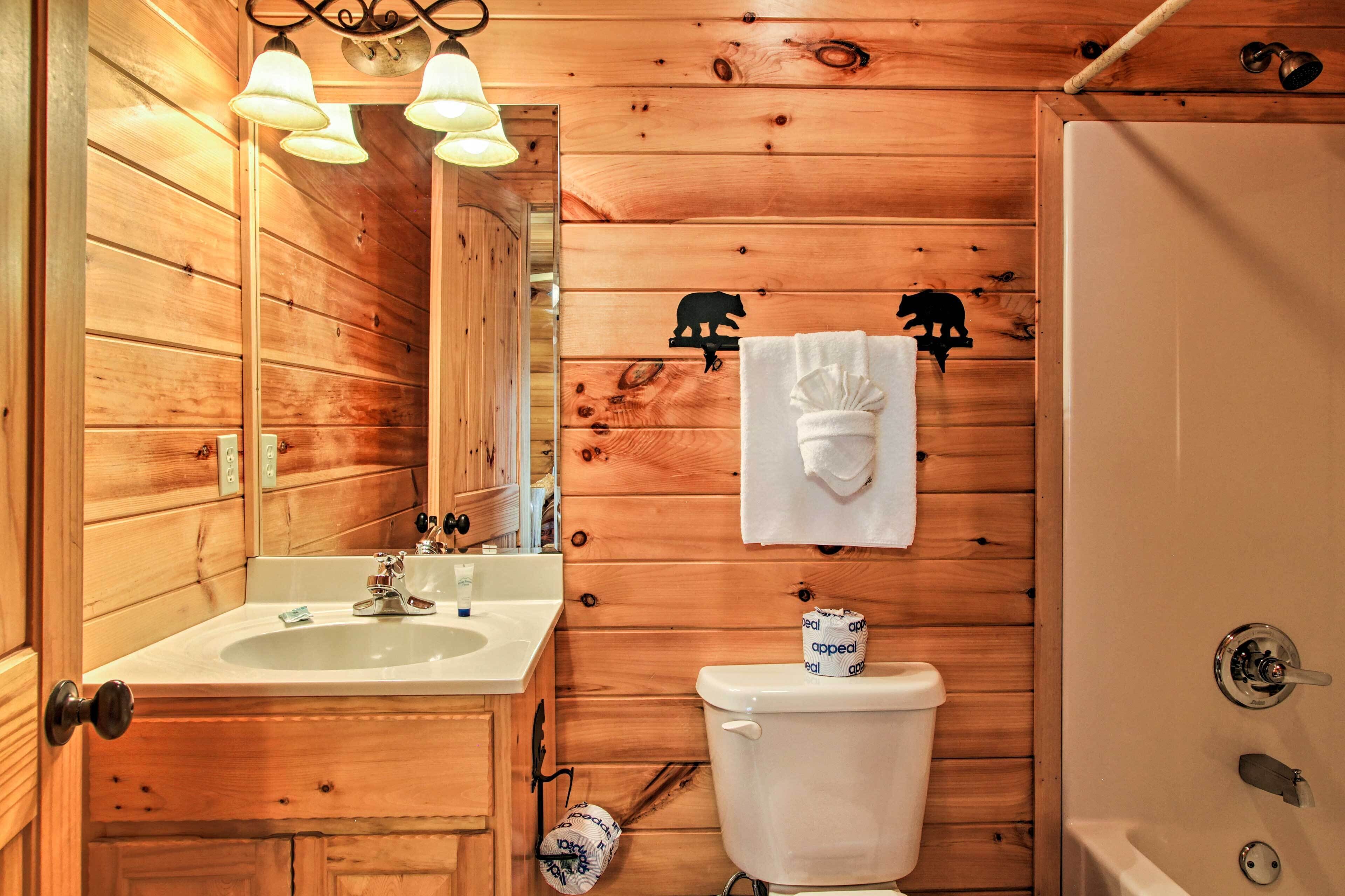 Baño de cabaña de madera con lavamanos, inodoro y ducha.