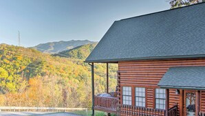 Une cabane en rondins avec un porche et une vue sur les montagnes en arrière-plan.