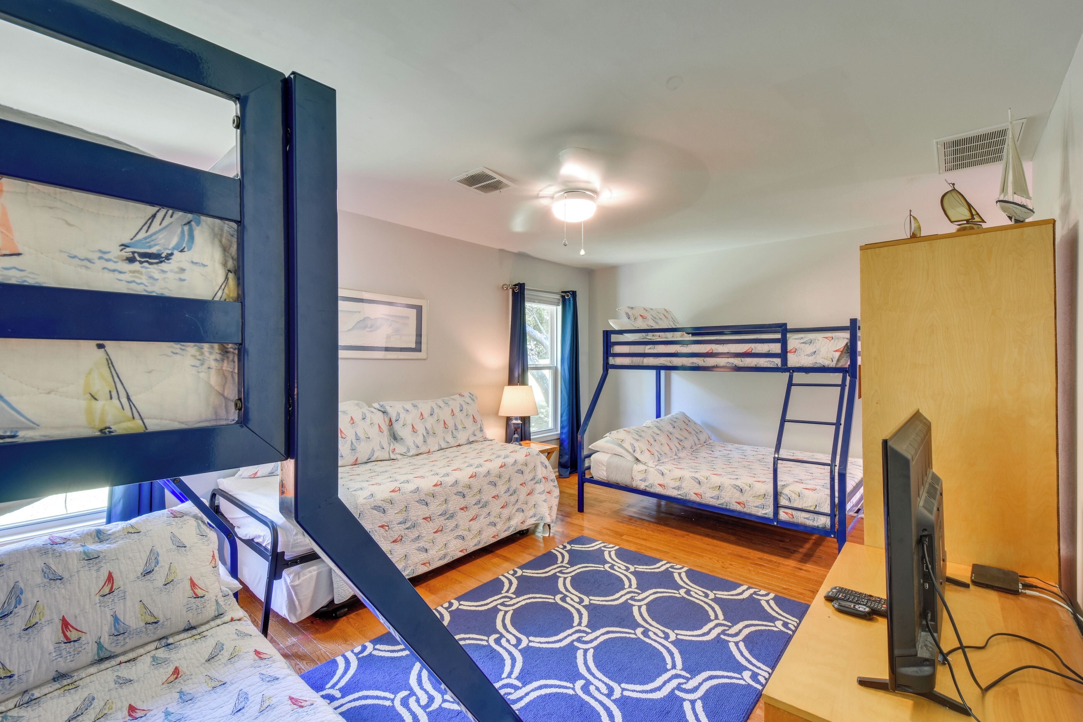 A room with bunk beds, a desk with a computer, and a window with curtains.