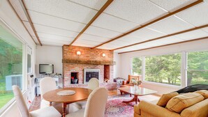 Amplia sala de estar con chimenea de ladrillo, una mesa de comedor y asientos cómodos.