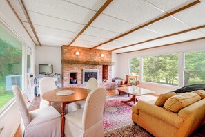 A spacious living area with a brick fireplace, a dining table, and comfortable seating. - Spacious Sullivan County House w/ Fire Pit (Hurleyville)