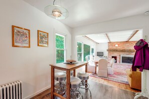 A dining area with a wooden table and bar stools, a hanging light fixture, and framed artwork on the wall. - Spacious Sullivan County House w/ Fire Pit (Hurleyville)