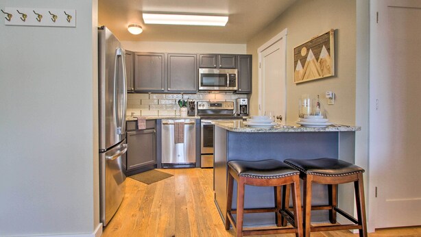 A kitchen with a refrigerator, microwave, dishwasher, and bar stools. - Cozy Montana Condo w/ Walk to Big Sky Resort! (Big Sky)