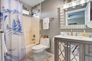 Ein Badezimmer mit Dusche, Toilette und Waschtisch mit Spiegel.