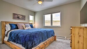 Un dormitorio con una cama grande, un ventilador de techo, un ventanal con vista a la playa y un armario de madera.