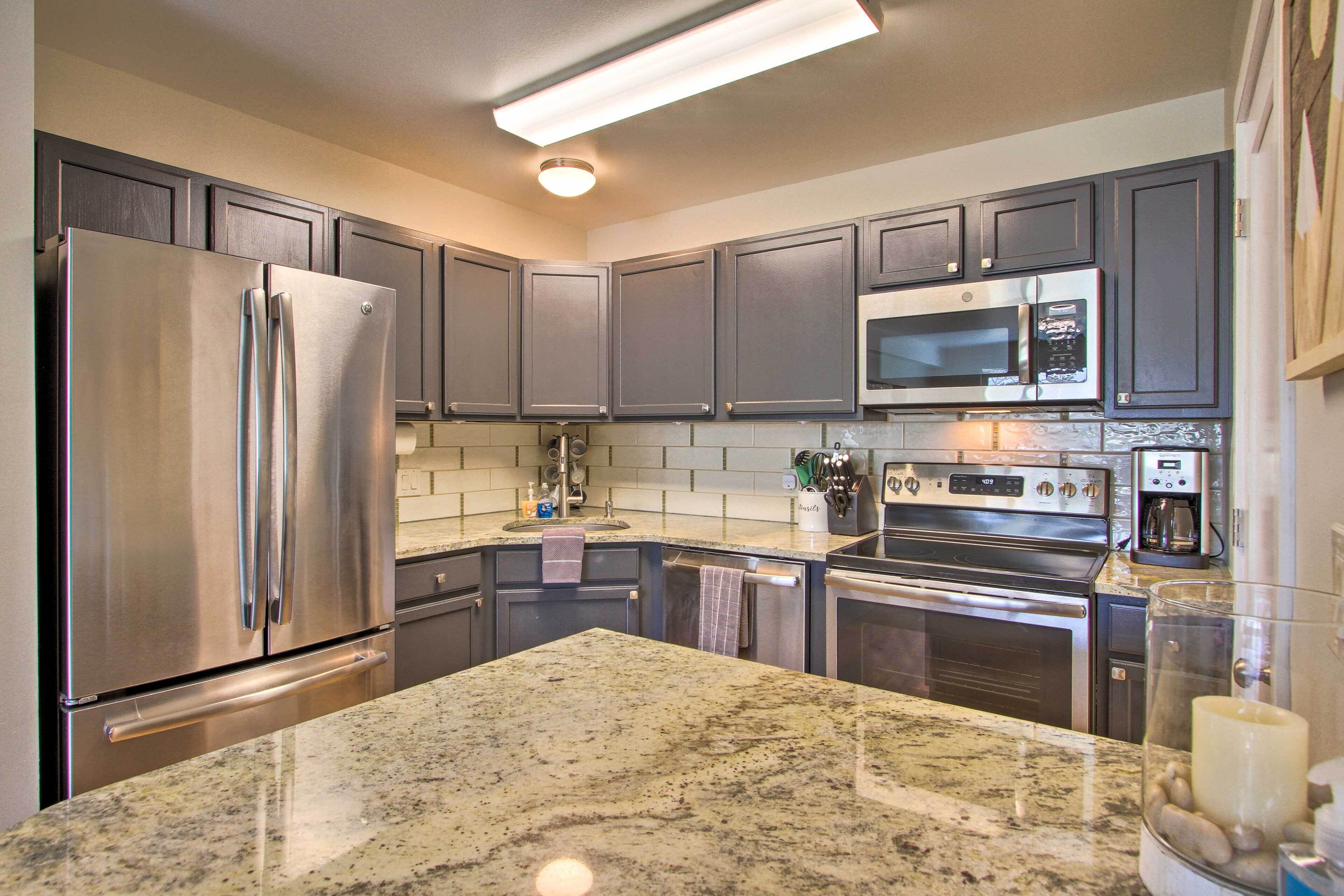 A modern kitchen with granite countertops, stainless steel appliances, and dark cabinetry.