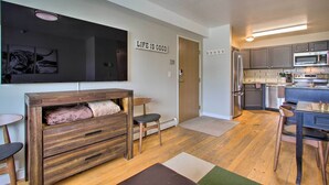 A compact living space with a kitchenette, a wooden cabinet, a flat-screen TV, and a "Life is Good" sign. - Cozy Montana Condo w/ Walk to Big Sky Resort! (Big Sky)