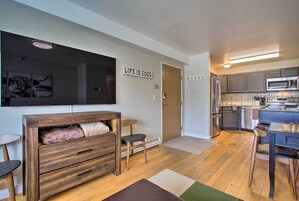 Un espacio habitable compacto con kitchenette, un mueble de madera, un televisor de pantalla plana y un cartel que dice “Life is Good”.