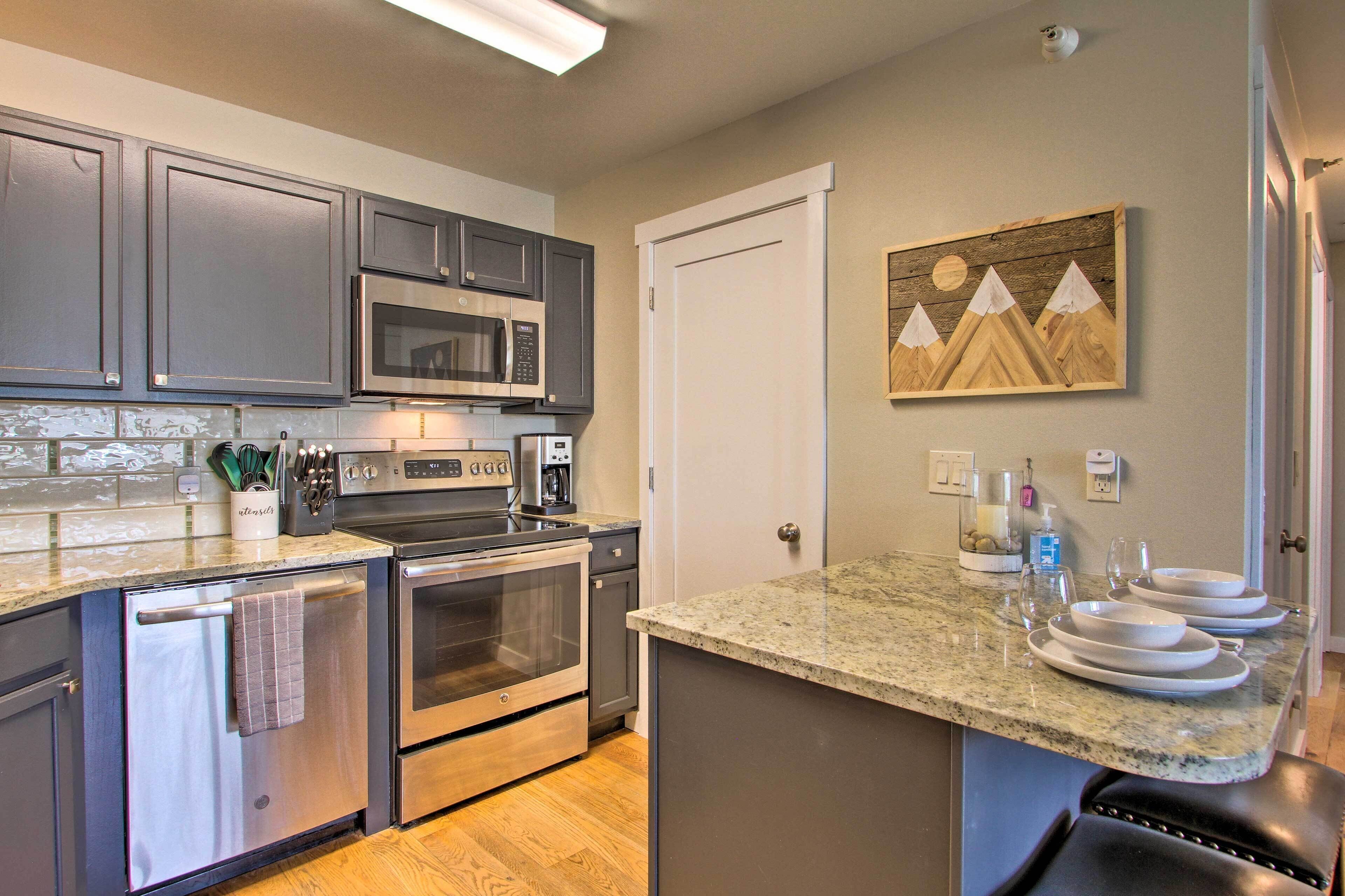 A modern kitchen with stainless steel appliances, granite countertops, and a wooden island with seating.