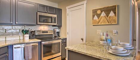 A modern kitchen with stainless steel appliances, granite countertops, and a wooden island with seating.