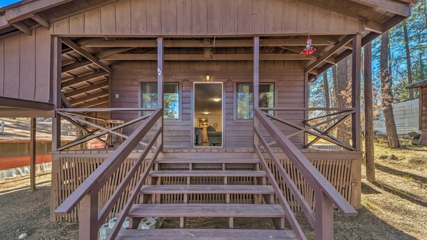 A wooden cabin with a staircase leading to a door, surrounded by trees. - Ruidoso Cabin - Walk to Midtown Dining & Shops! (Ruidoso)
