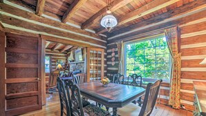 A rustic wooden dining room with a large table, chairs, and a window with curtains. - Rustic Dover Retreat w/ Porch - Walk to Boat Ramp! (Dover)