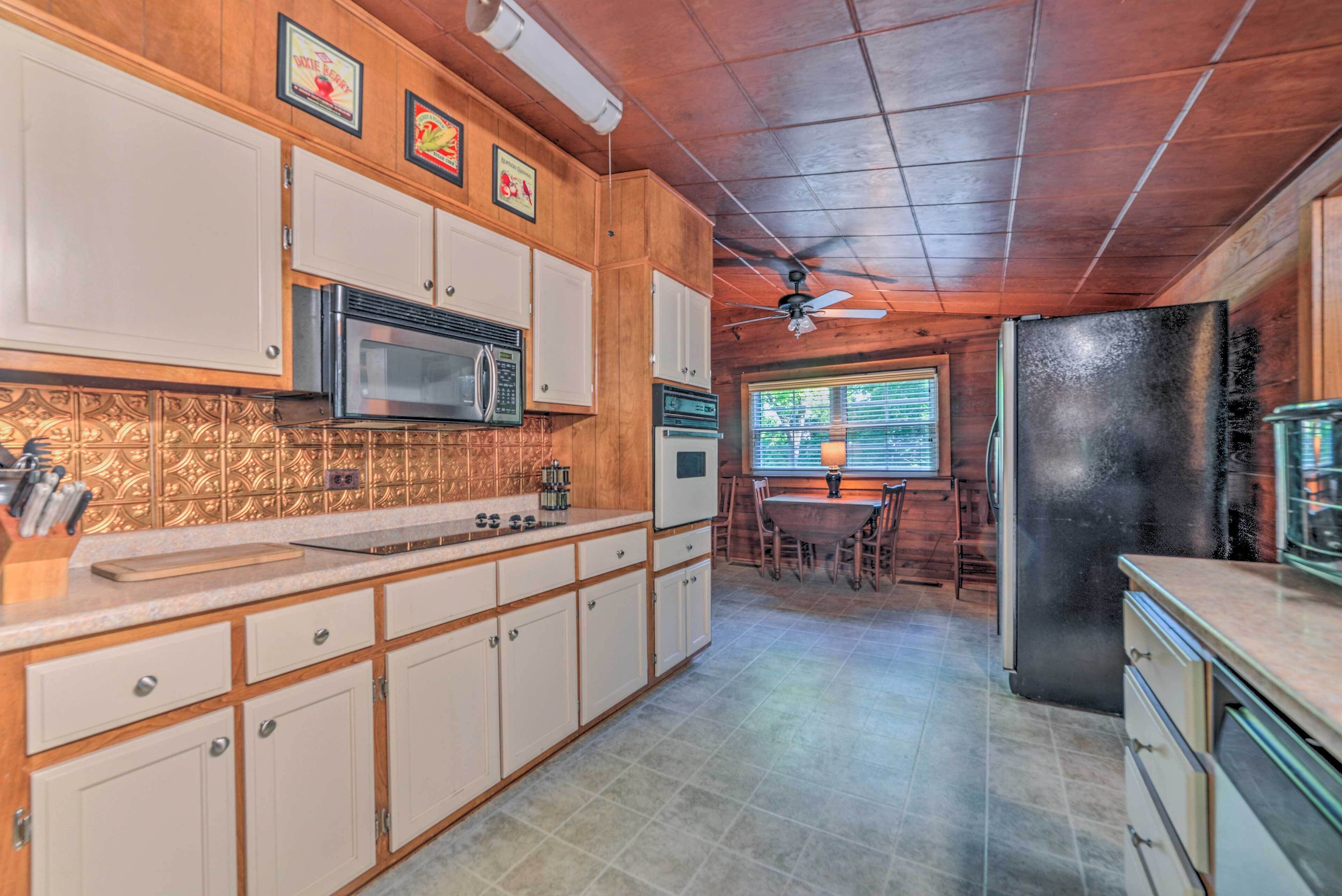 A kitchen with wooden cabinets, a microwave, a refrigerator, and a dining area with a table and chairs.