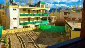 A multi-story building with balconies, a flat roof, and a mountainous backdrop. - Hotel RI Rab (Leh)