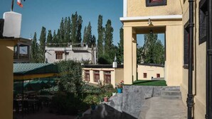 A courtyard with outdoor seating, a flag, and buildings with a traditional architectural style. - Hotel RI Rab (Leh)