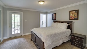 A bedroom with a bed, a nightstand, a door with a view, and a ceiling light. - Gulfport Condo w/ Private Balcony - Walk to Beach! (Gulfport)