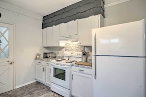 Una cocina con gabinetes blancos, un refrigerador blanco, una estufa y un tostador.