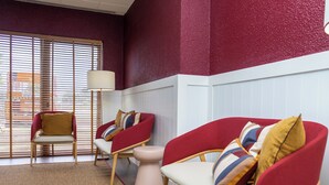 A modern living room with two red sofas, a wooden chair, and a floor lamp. - Flag Hotel Lisboa Oeiras (Oeiras)