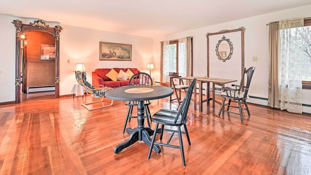 A spacious room with a wooden floor, a round dining table with chairs, a red sofa, and a large mirror. - Old Time Catskill Mtn Retreat, Handcrafted Cabin! (East Durham)
