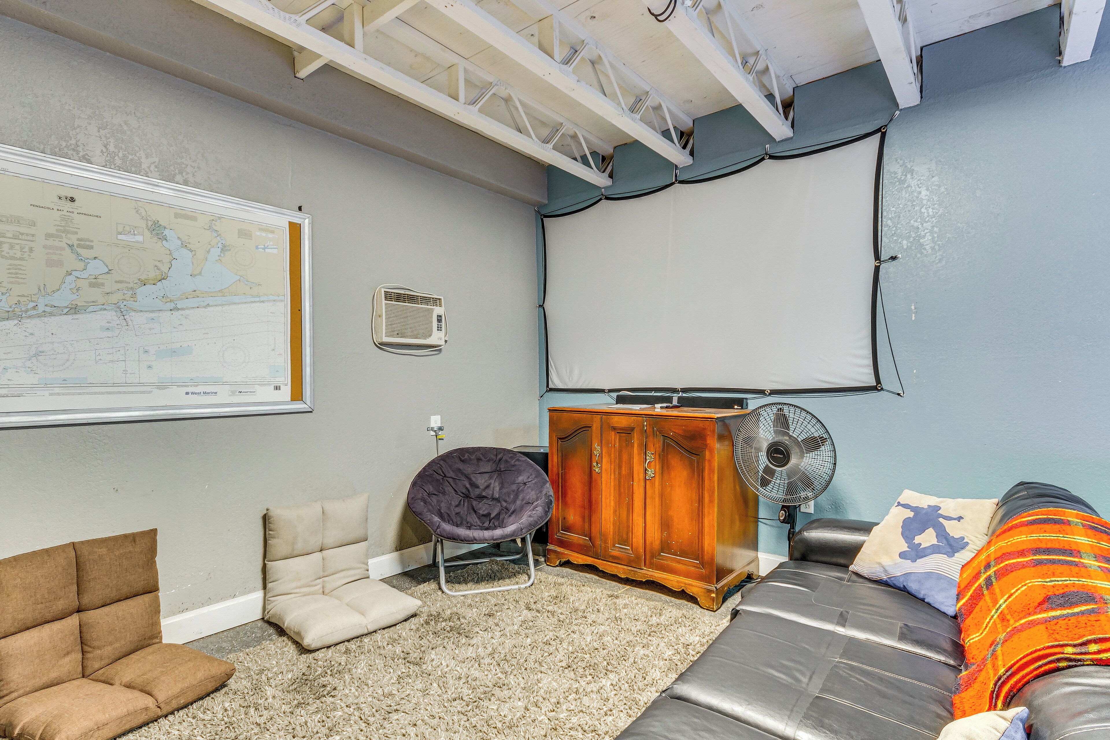 A room with a large map on the wall, a sofa, a chair, a cabinet, and a fan.
