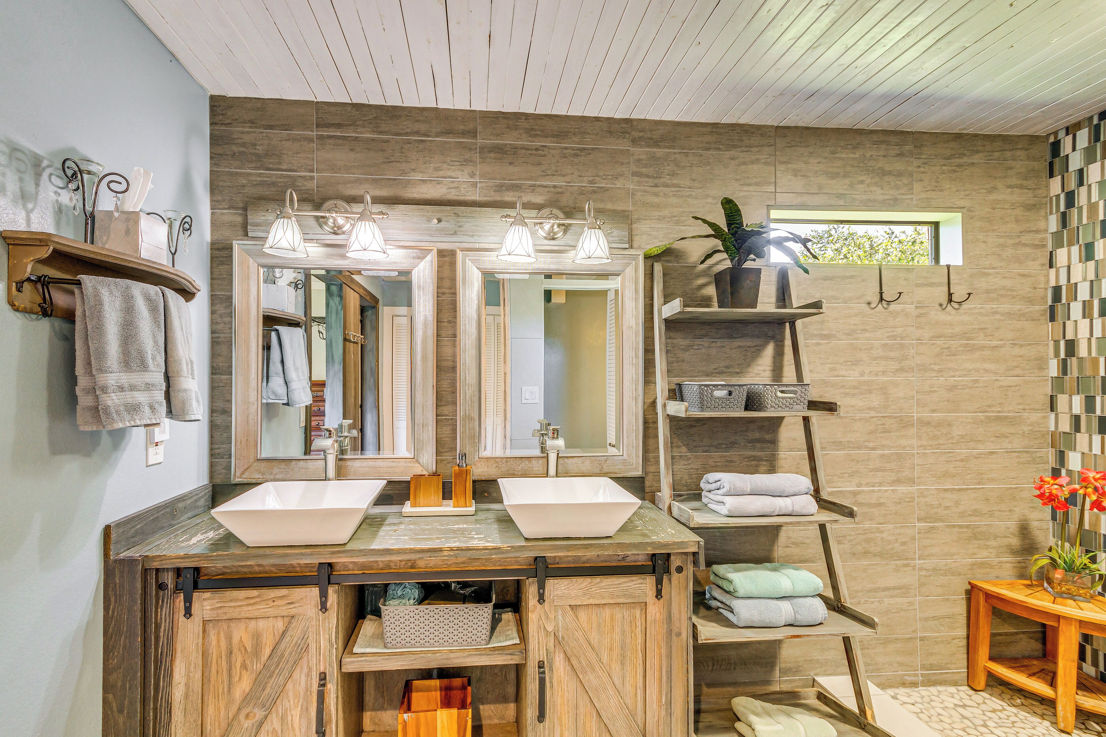 Un baño con tocador de madera, dos lavamanos y un espejo grande.